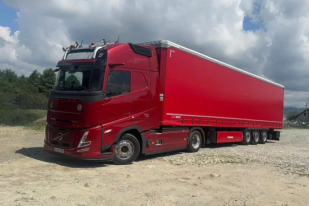 Cap tractor Volvo de ultima generatie si semiremorca mega cu prelata fotografiate la garajul firmei